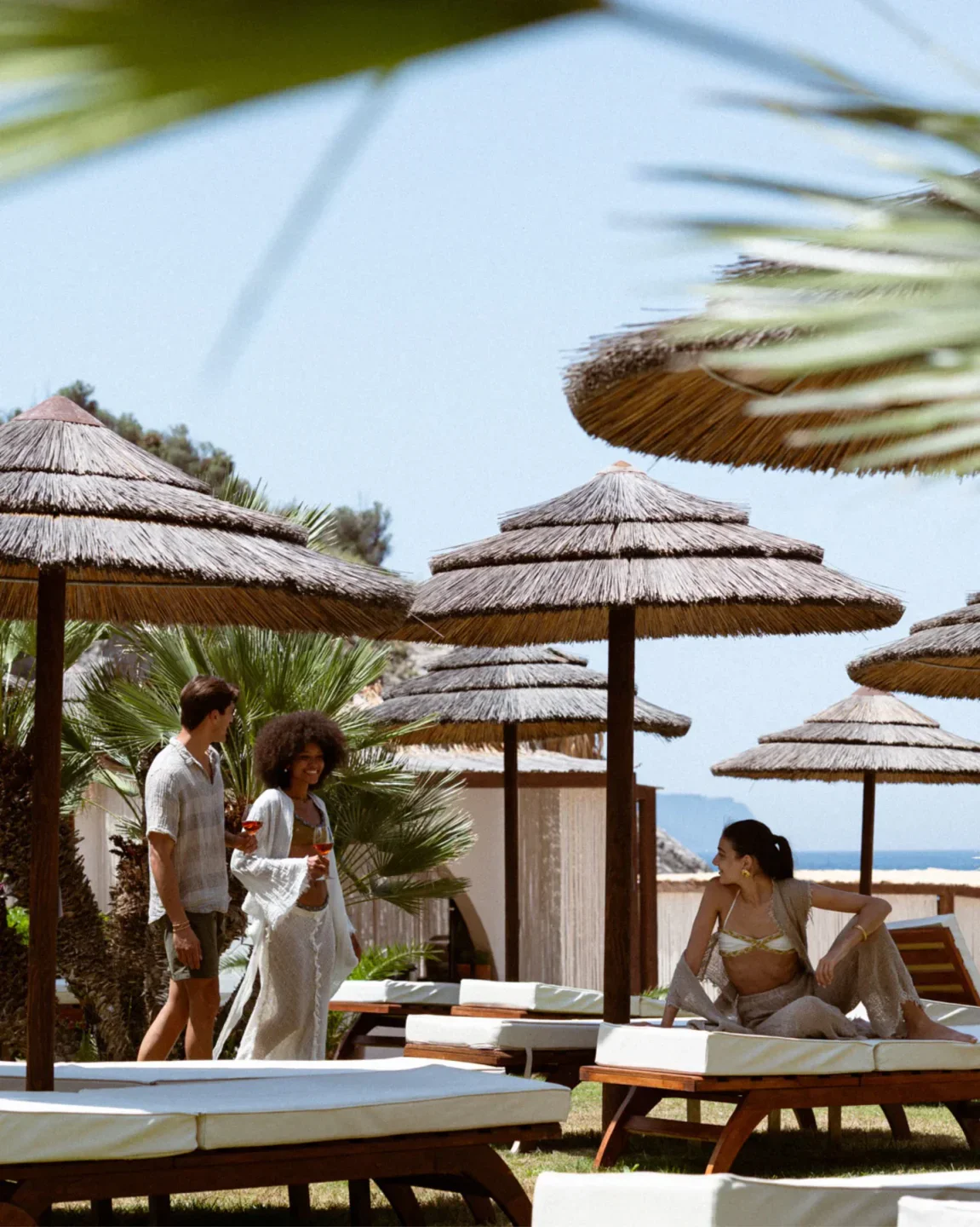 Couple enjoying drinks at Maya Beach Experience, a beachfront restaurant on the Amalfi Coast with thatched umbrellas.